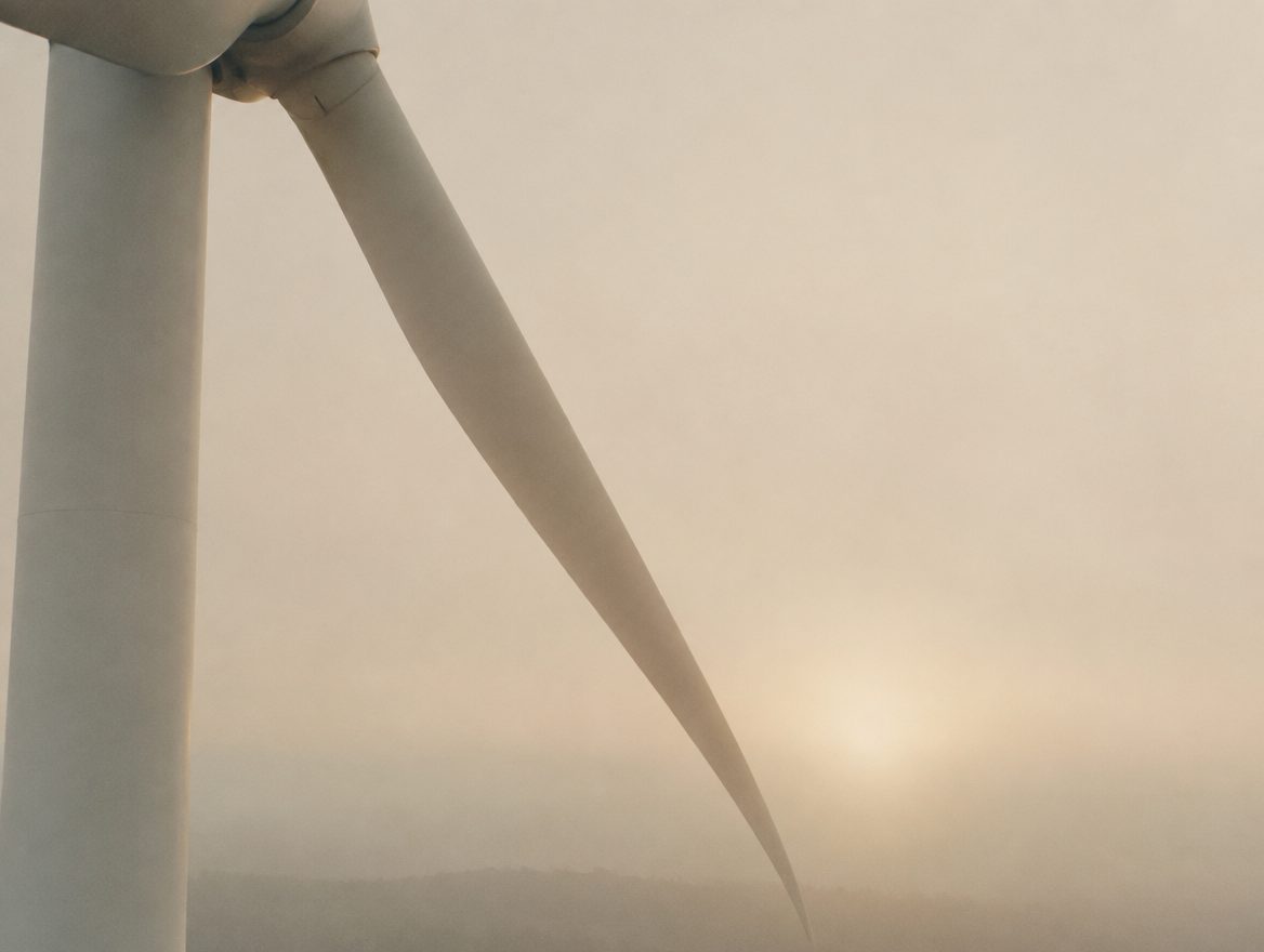 White wind turbine blade in pale morning fog